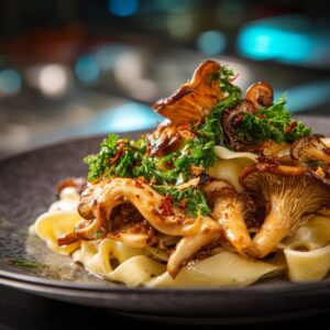 Close-up of a plate of pasta topped with sautéed oyster mushrooms, fresh herbs, and chili flakes