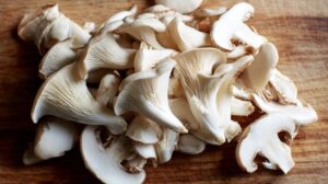 Close-up of raw oyster mushrooms on a wooden surface, showing their delicate gills and caps