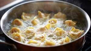 Wontons cooking in boiling water inside a pan with steam rising