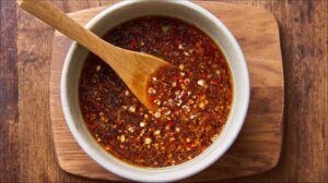 Bowl of lemongrass beef marinade with garlic, chili, and spices stirred with a wooden spoon