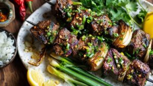 Grilled lemongrass beef kabobs with onions, garnished with green herbs and chili flakes, served on a plate with rice and lemon wedges