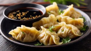 Plate of freshly steamed wontons garnished with herbs, served with soy dipping sauce