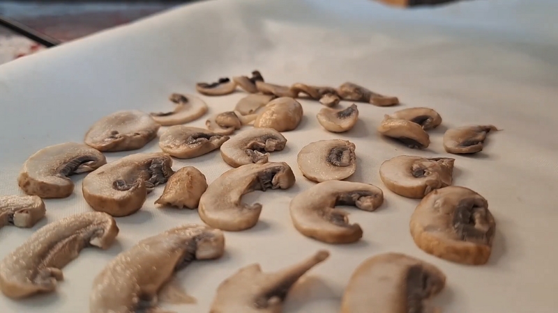 Cooked mushroom slices cool on a tray before proper freezer storage