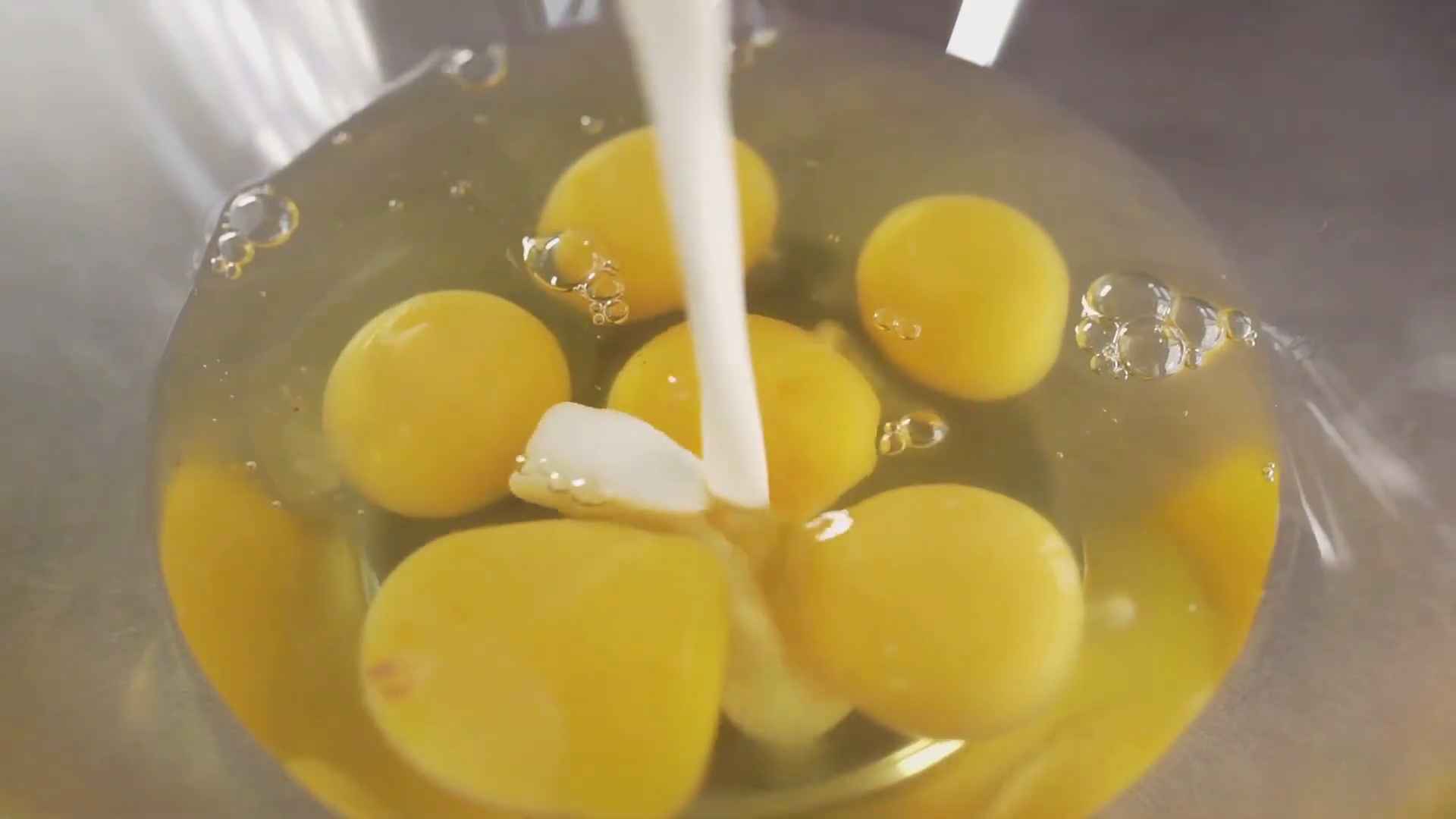Multiple bright yellow ostrich egg yolks in a clear bowl