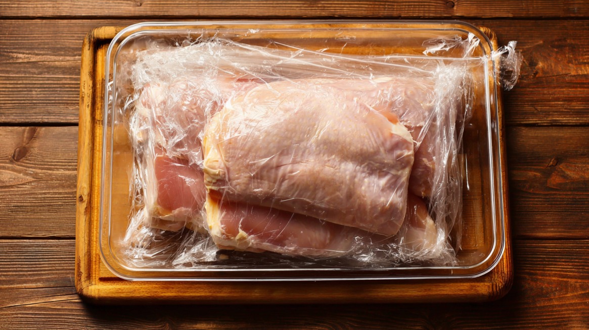 Raw turkey breast wrapped in plastic on a tray