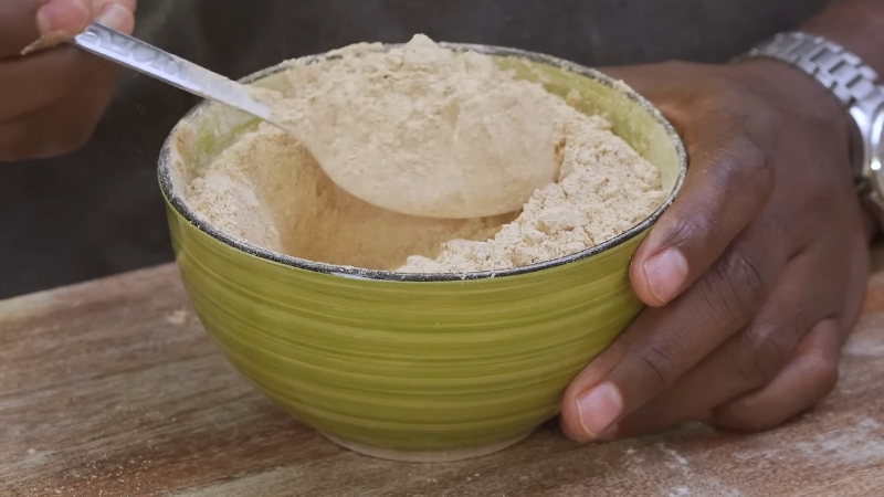 Person scooping mushroom powder from a green bowl with a spoon